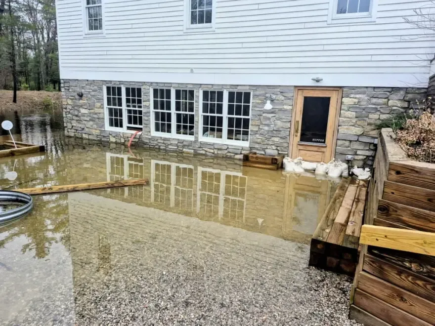Stormwater pooled beside a walkout basement with sandbags at the door
